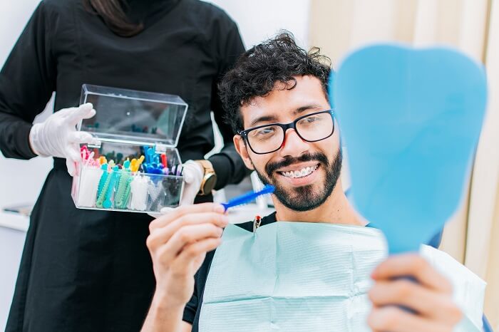 Dentista com mostruário de cores de borrachinha de aparelho, enquanto paciente escolhe.