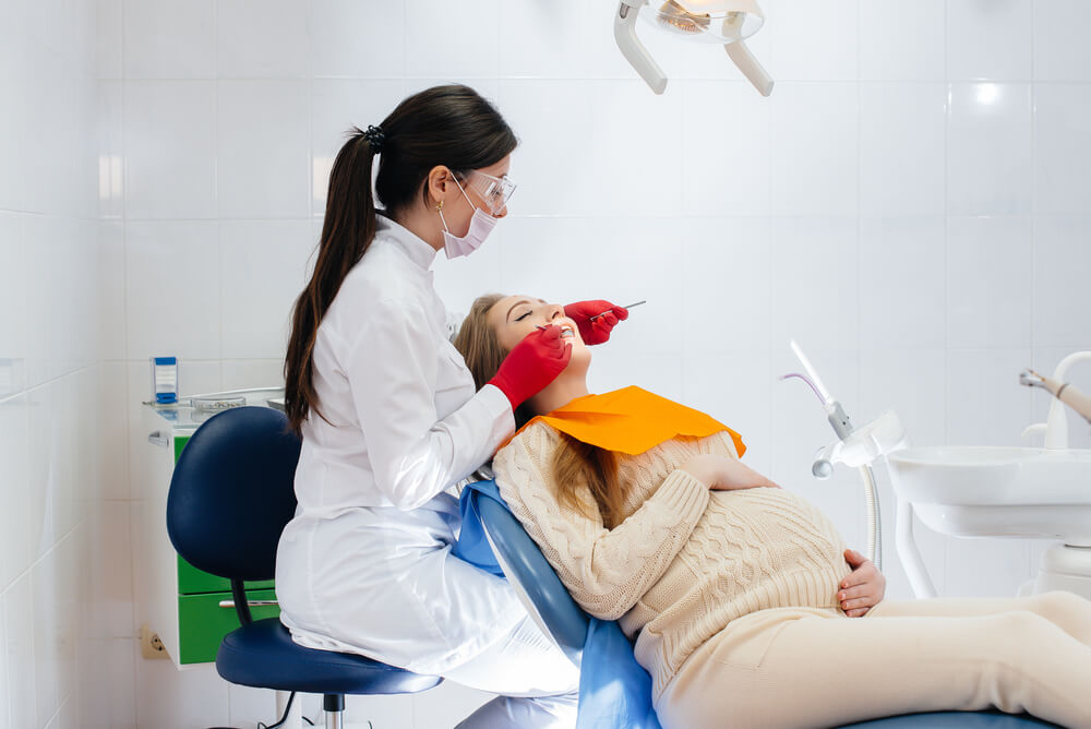 Imagem de uma dentista atendendo uma paciente que está grávida.