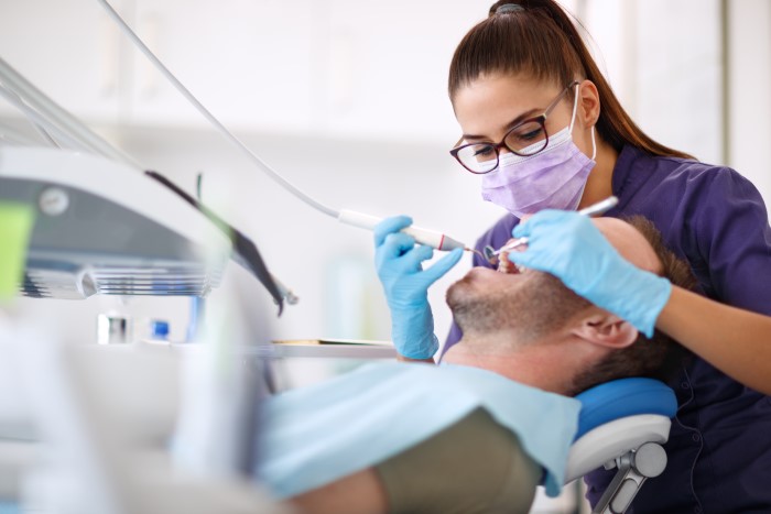 Dentista utilizando brocas odontológicas em tratamento.