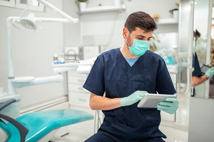 Dentista em consultório mexendo em tablet