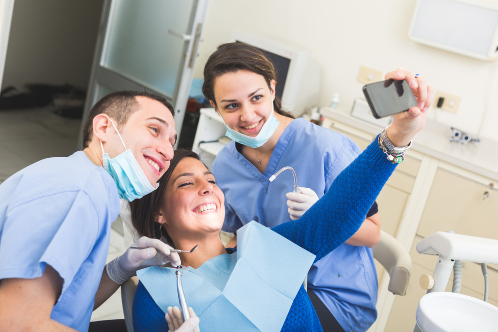 Paciente tirando selfie com dentista e auxiliar