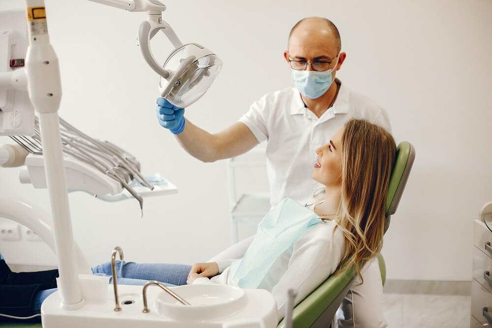 dentista ajustando o refletor para o início do tratamento do paciente.