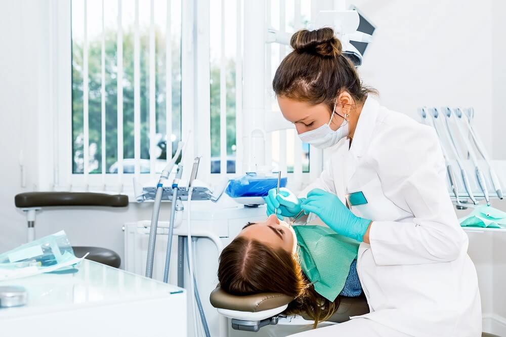 Mulher branca dentista realizando procedimento odontológico