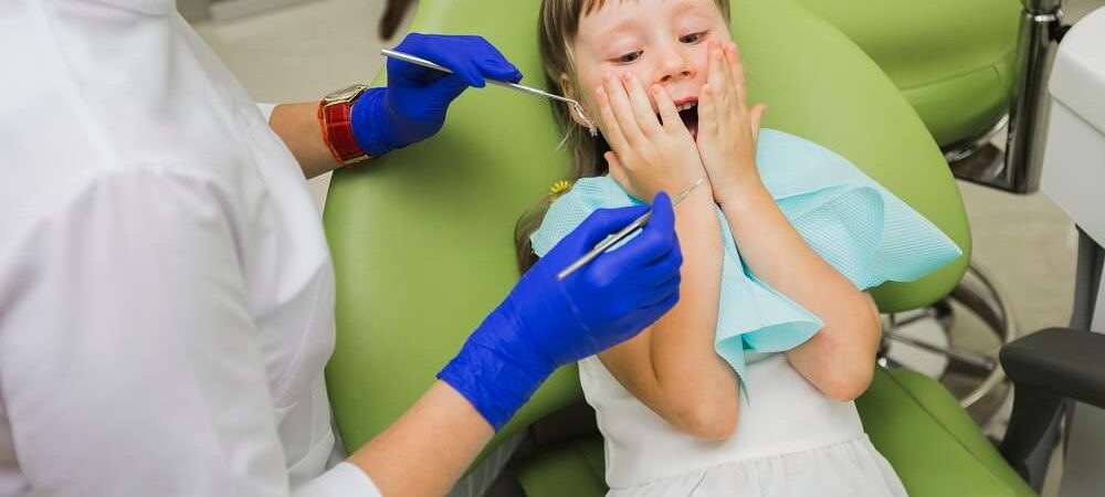 Criança com odontofobia deitada na cadeira odontológica