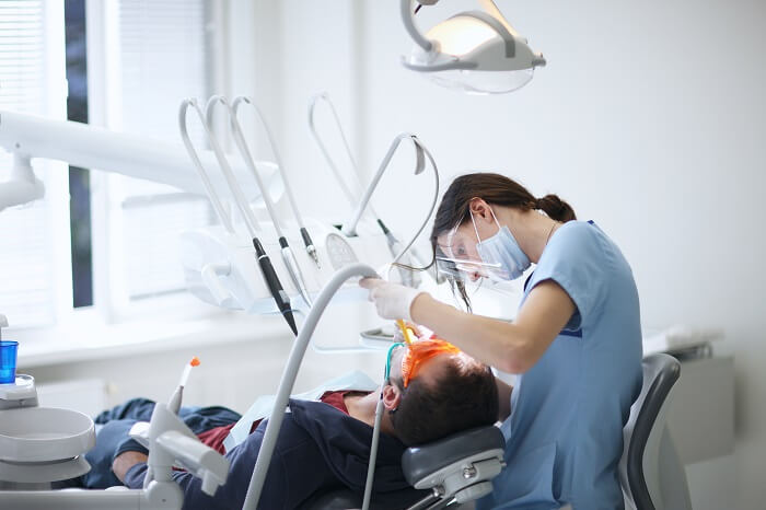 Mulher branca dentista fazendo procedimento odontológico em paciente