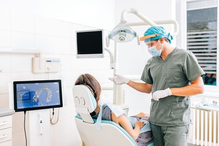 Homem dentista realizando procedimento odontológico em mulher