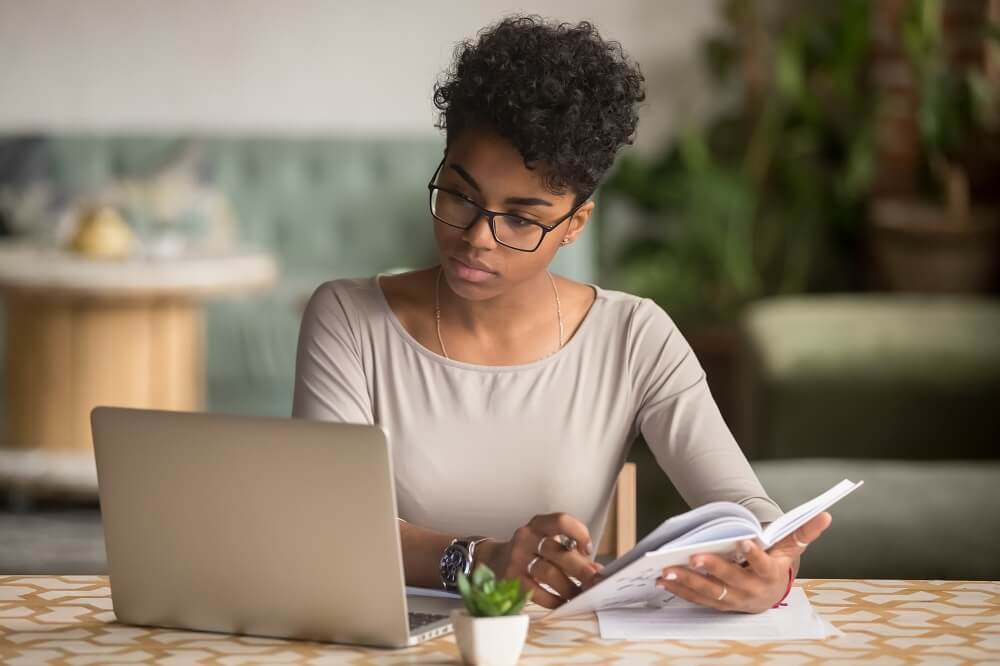 Mulher negra fazendo anotações enquanto está em notebook