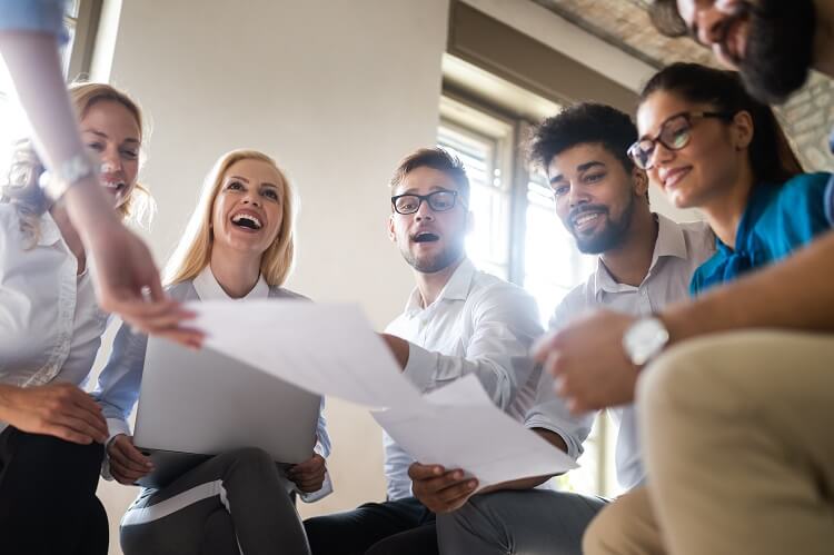 Grupo de pessoas de diferentes etnia, em roda, com papéis na mão