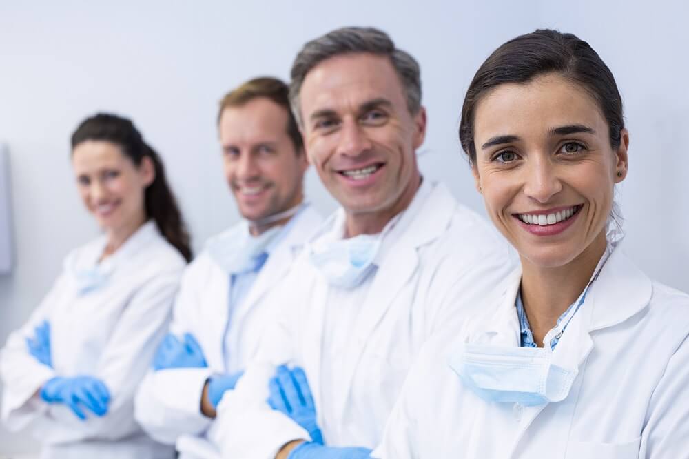 Grupo de dentistas olhando para a câmera e sorrindo