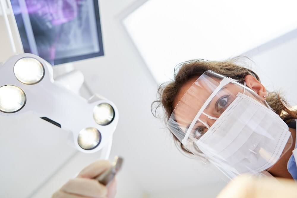 Dentista com face shield analisando paciente