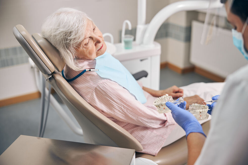 Idosa em consulta odontológica, cadeira reclinada.