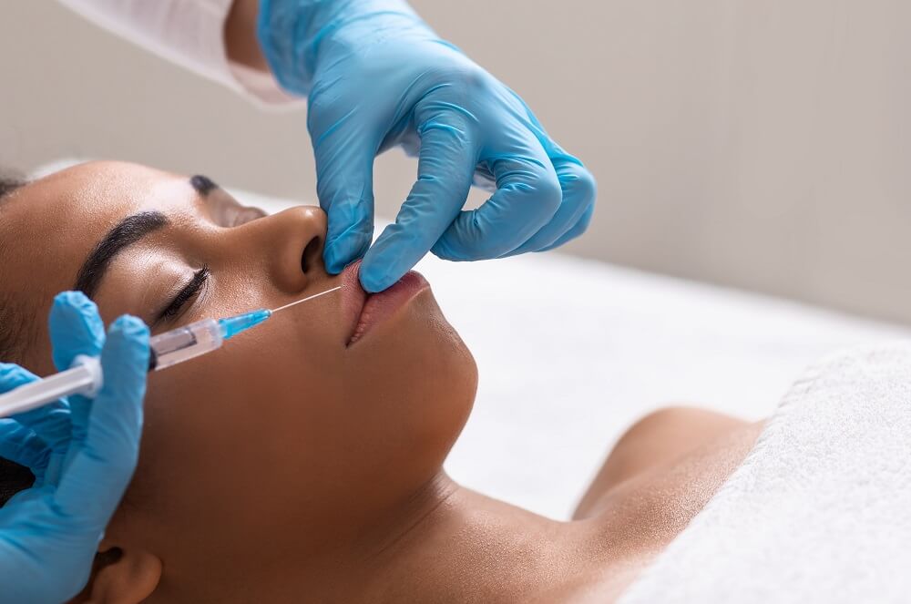 Mulher negra recebendo aplicação de produto na boca