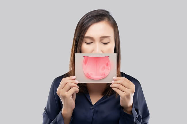 Mulher segurando placa com emoji de lingua em frente a boca