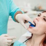Pessoa com boca aberta enquanto dentista faz molde dos dentes