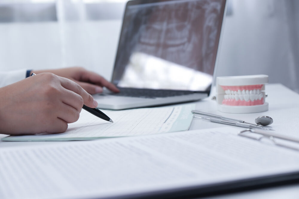 Mão escrevendo sobre documentos em ambiente profissional.