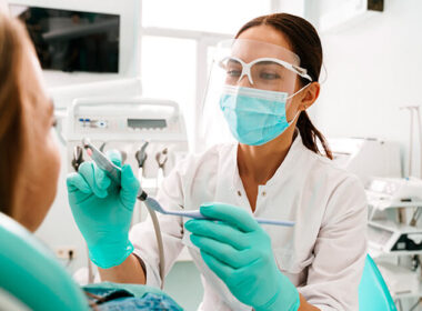 dentista em atendimento a uma paciente do gênero feminino utilizando aparelhos que passaram por manutenção de equipamentos odontológicos