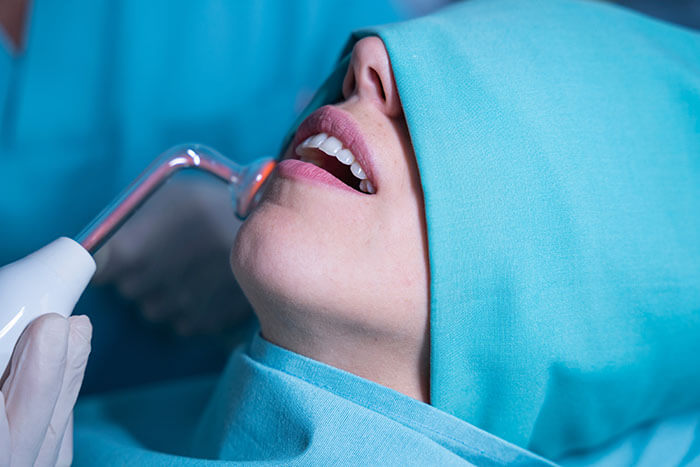 dentista usando ozonioterapia na odontologia em uma paciente mulher.