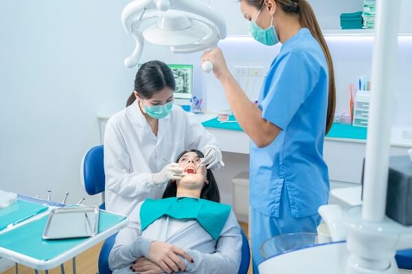 Dentista e auxiliar realizando atendimento.