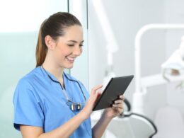 Dentista lendo um tablet com resumos de odontologia.