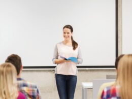 Acadêmica realiza apresentação de trabalhos com livro na mão em faculdade de odontologia.
