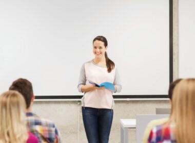 Acadêmica realiza apresentação de trabalhos com livro na mão em faculdade de odontologia.