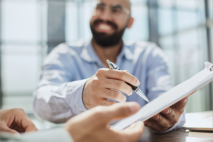 Homem Sorrindo com uma caneta e uma prancheta na mao