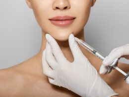 Cirurgião-dentista faz aplicação do bioestimulador Rennova com seringa no queixo de paciente.