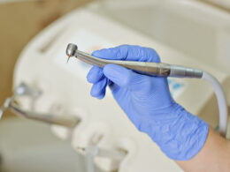 Dentista com luva segurando canteta odontológica.