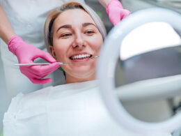 dentista com luvas descartáveis de cor rosa fazendo tratamento dentário em uma paciente mulher