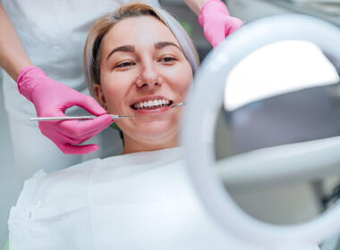 dentista com luvas descartáveis de cor rosa fazendo tratamento dentário em uma paciente mulher