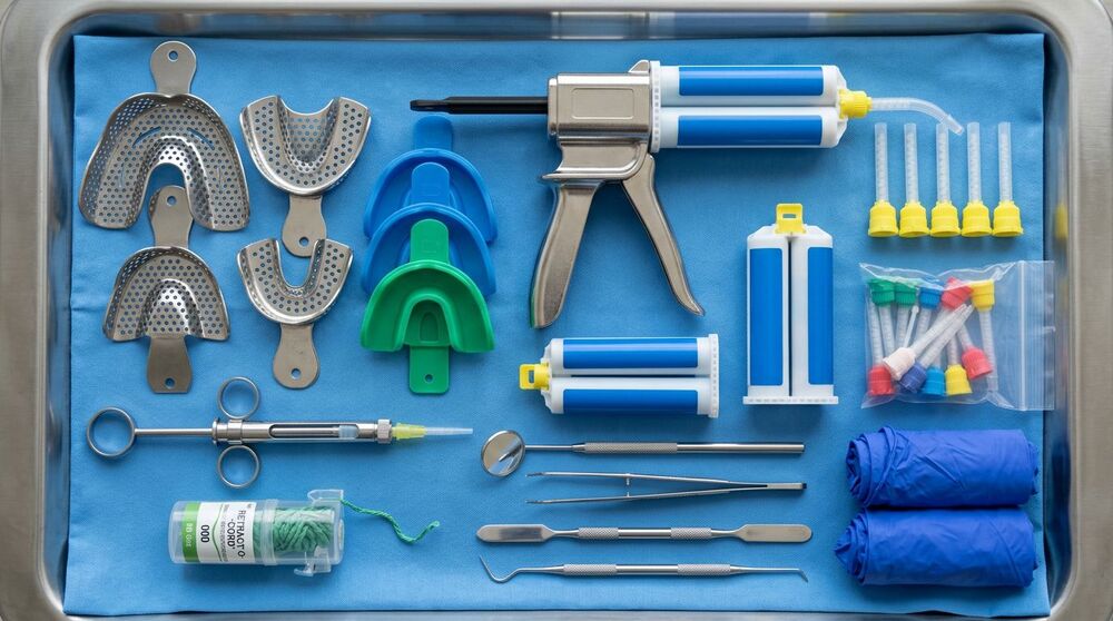 Conjunto de ferramentas dentárias organizadas, incluindo moldes e seringas.
