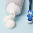 Creme dental e escova de dentes sobre fundo azul.