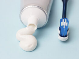 Creme dental e escova de dentes sobre fundo azul.