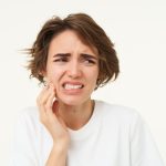 Jovem com dor de dente e expressão de desconforto