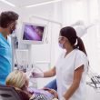Dois dentistas examinando paciente em uma maca