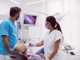 Dois dentistas examinando paciente em uma maca