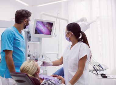 Dois dentistas examinando paciente em uma maca