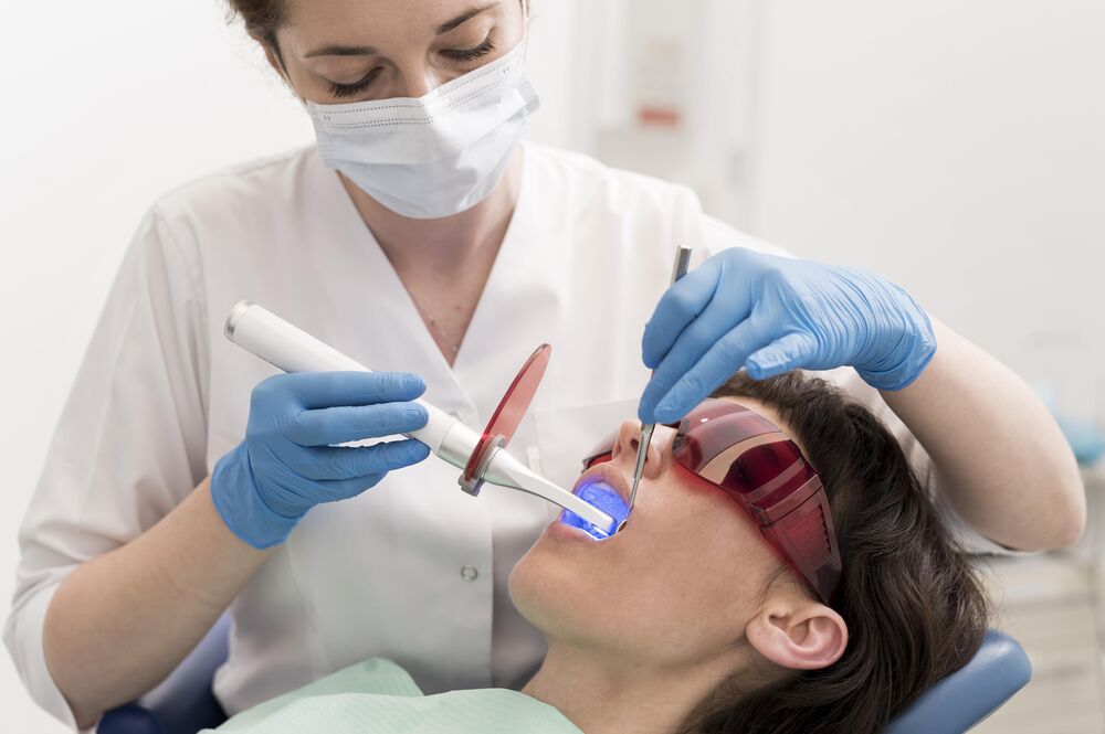 Dentista realizando tratamento dental com laser.